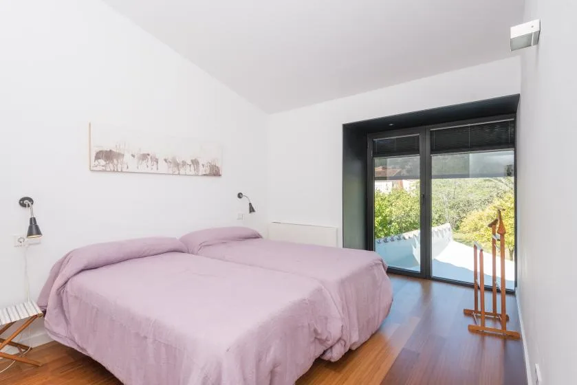 Un dormitorio con dos camas cubiertas con ropa de cama rosa claro junto a una ventana grande.