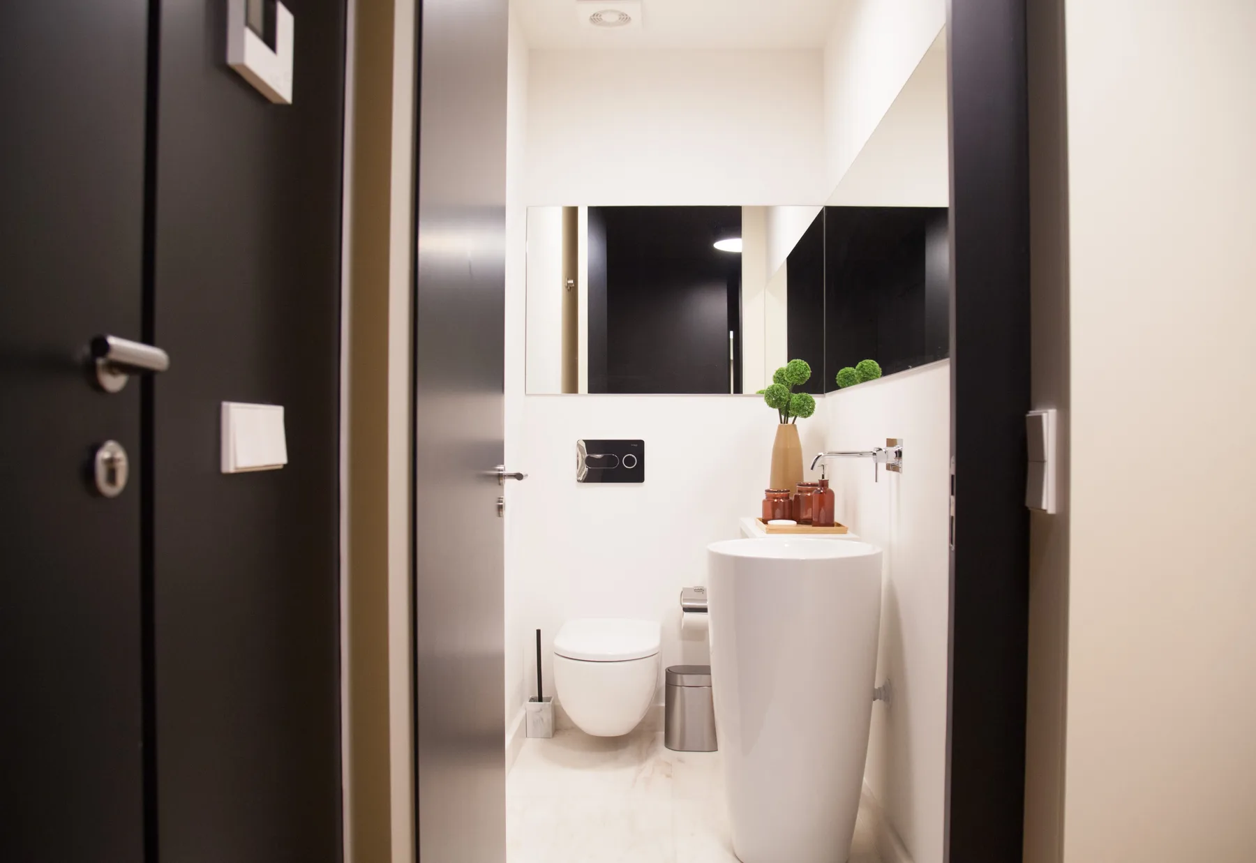 A modern bathroom with a toilet and a white pedestal sink.