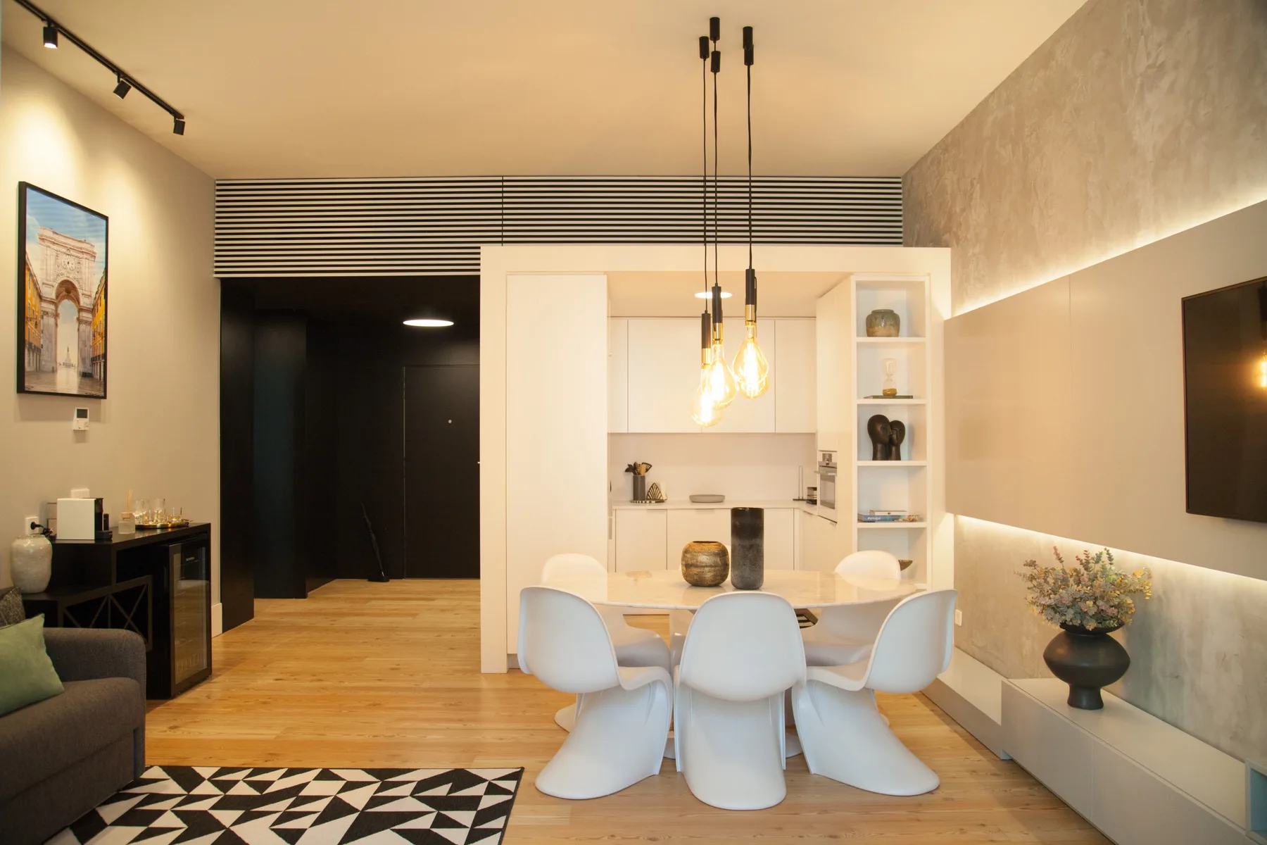An open-plan kitchen and dining area with a table and pendant lights.