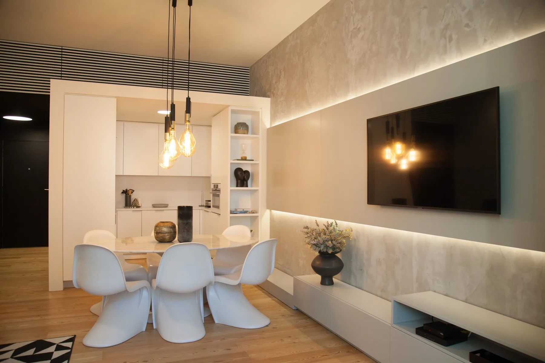 A dining area with pale seating and a wall-mounted television.