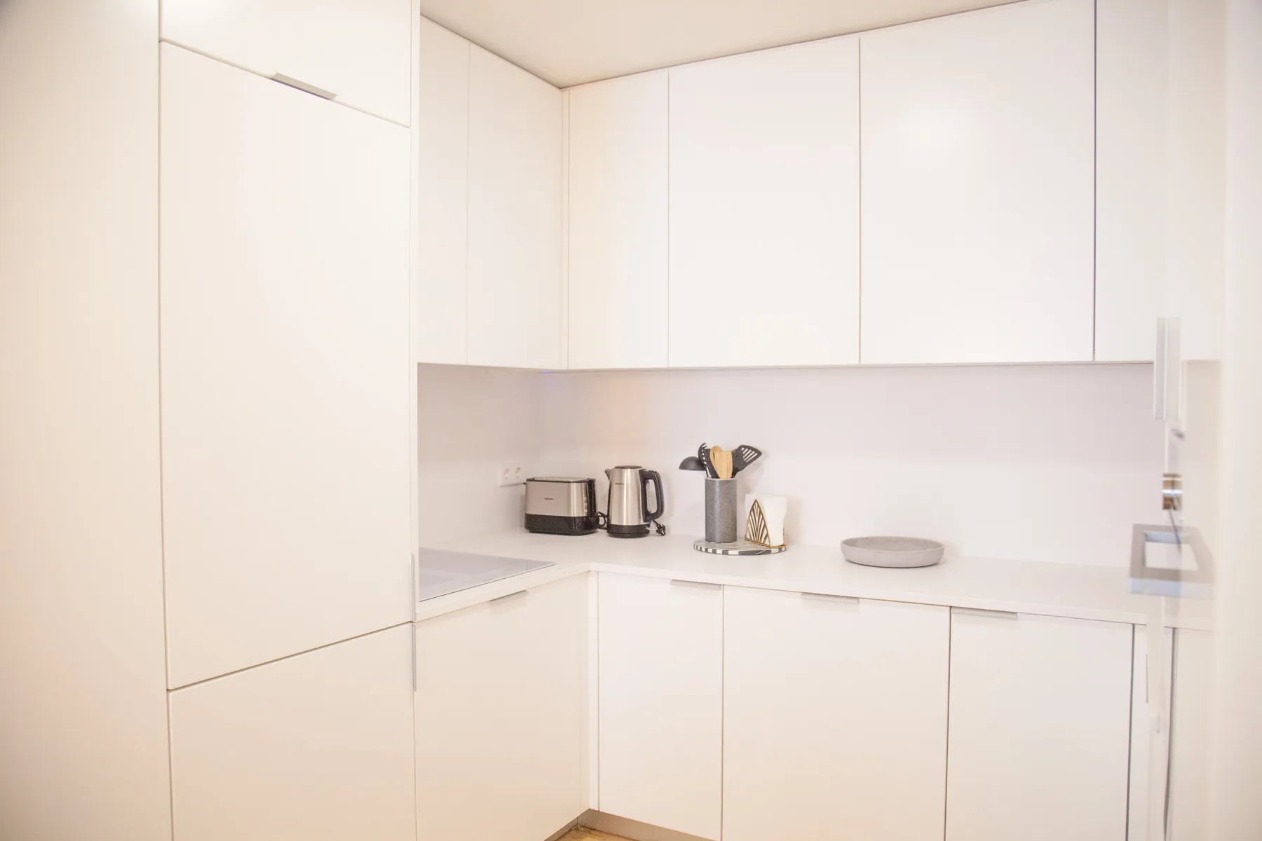 A bright white kitchen with cabinets and a countertop.