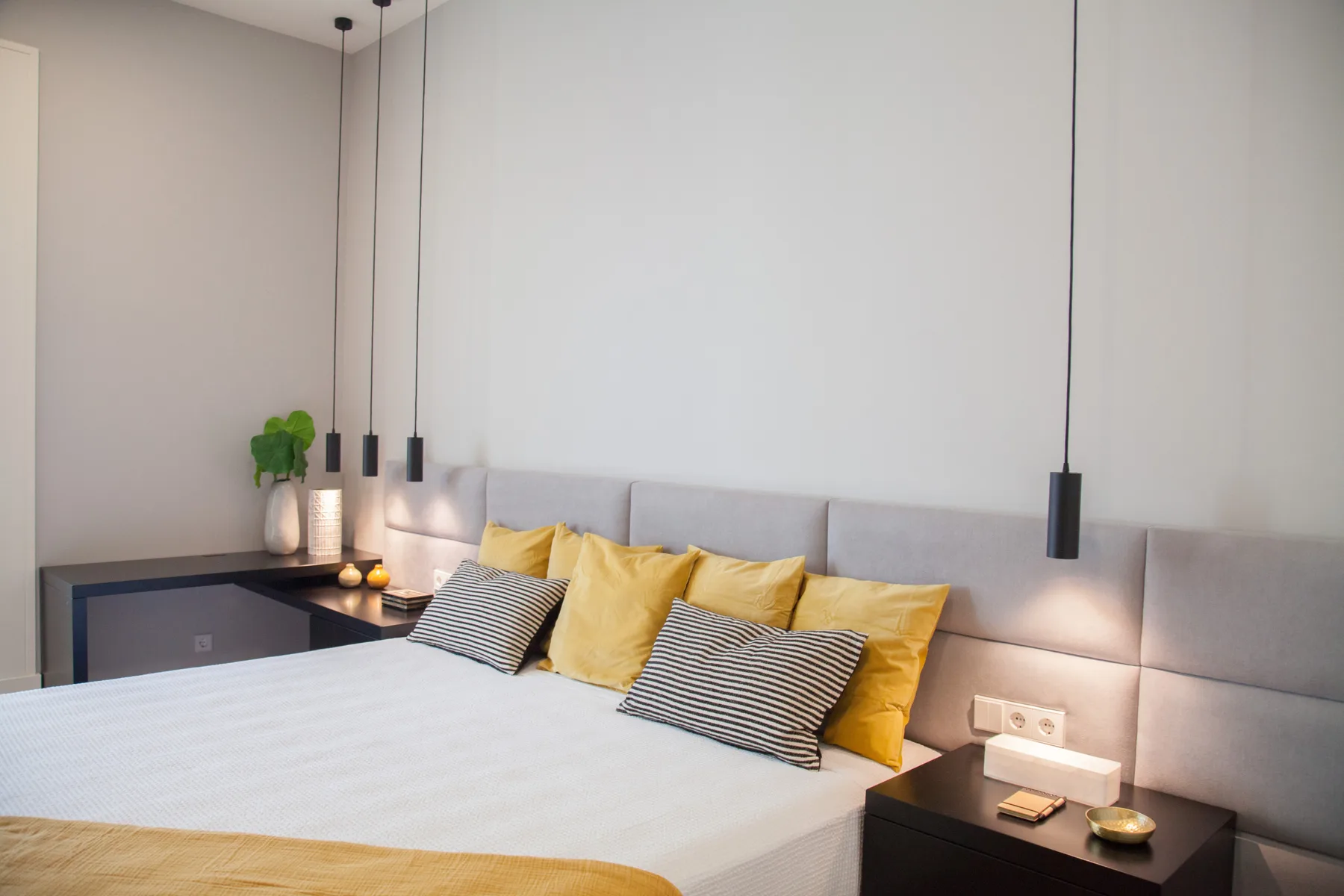 A bedroom with a bed, mustard-colored pillows, and bedside tables.