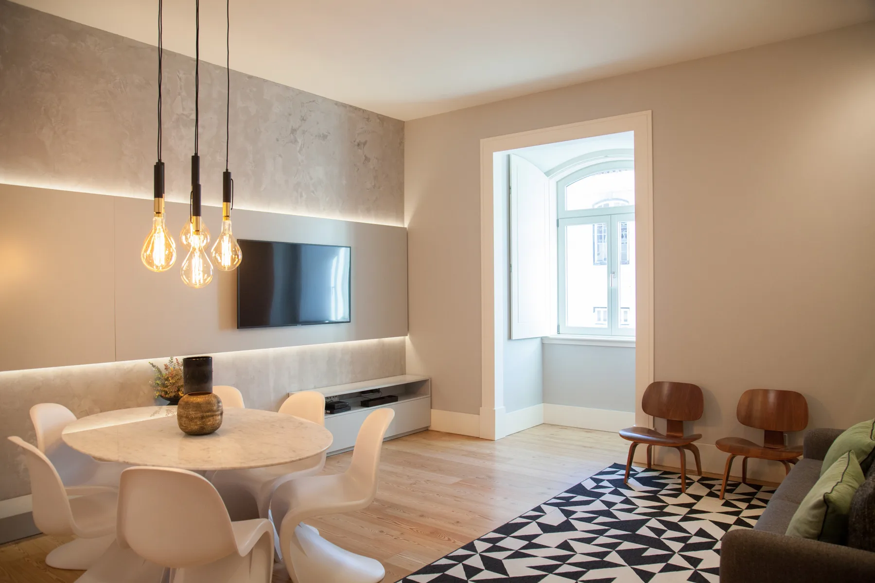 A modern living and dining room with a television and seating.