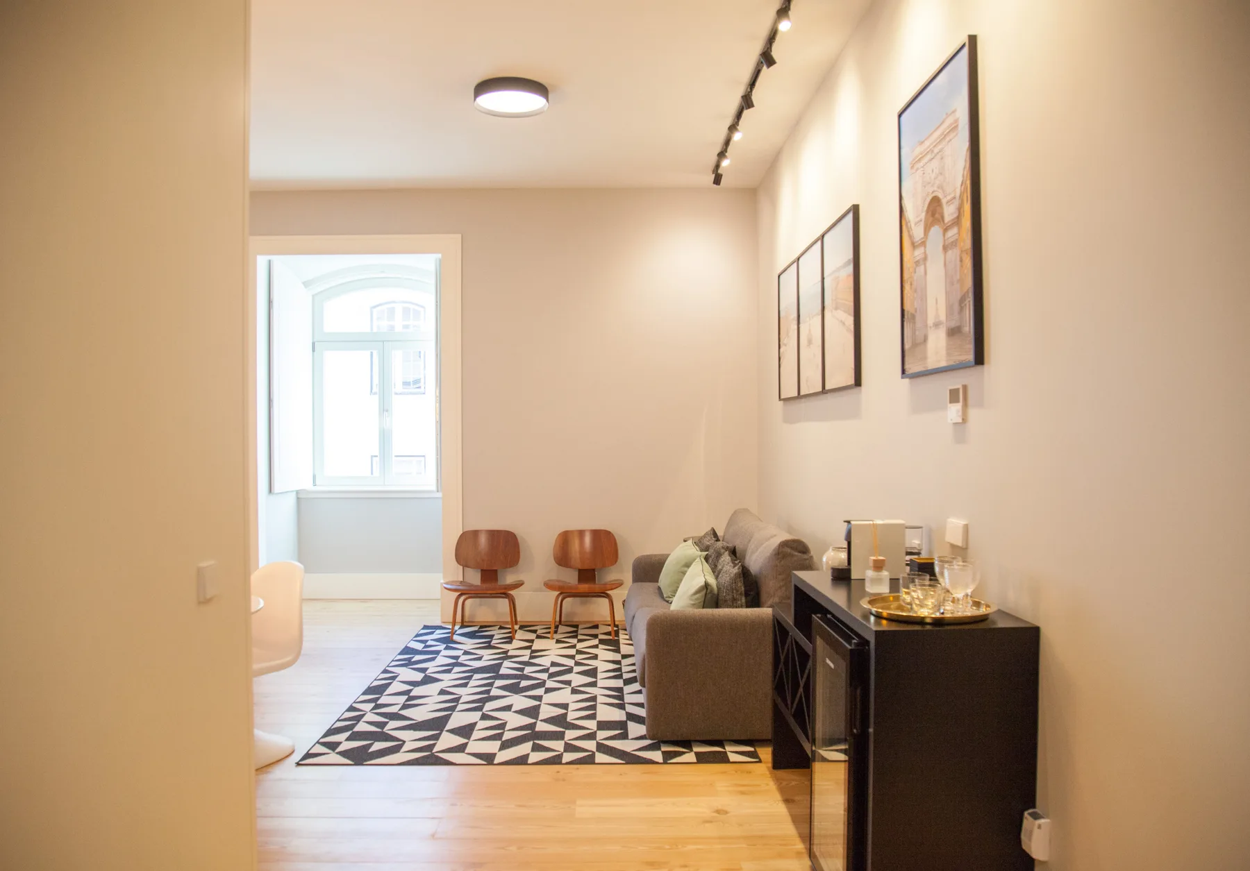 A living room with seating, framed artwork, and a patterned rug.