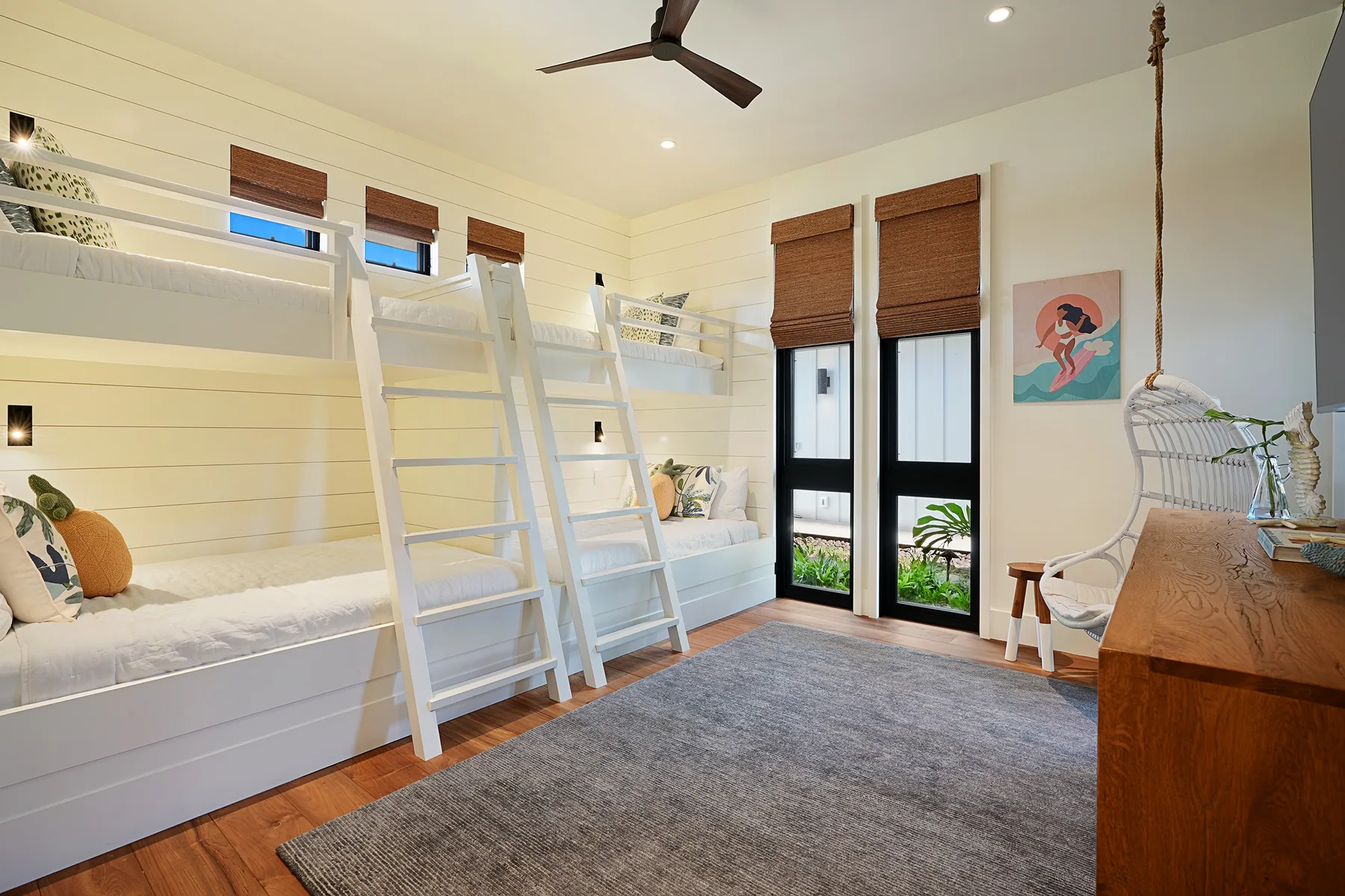 Un dormitorio luminoso con literas integradas, ventanas grandes y una alfombra.
