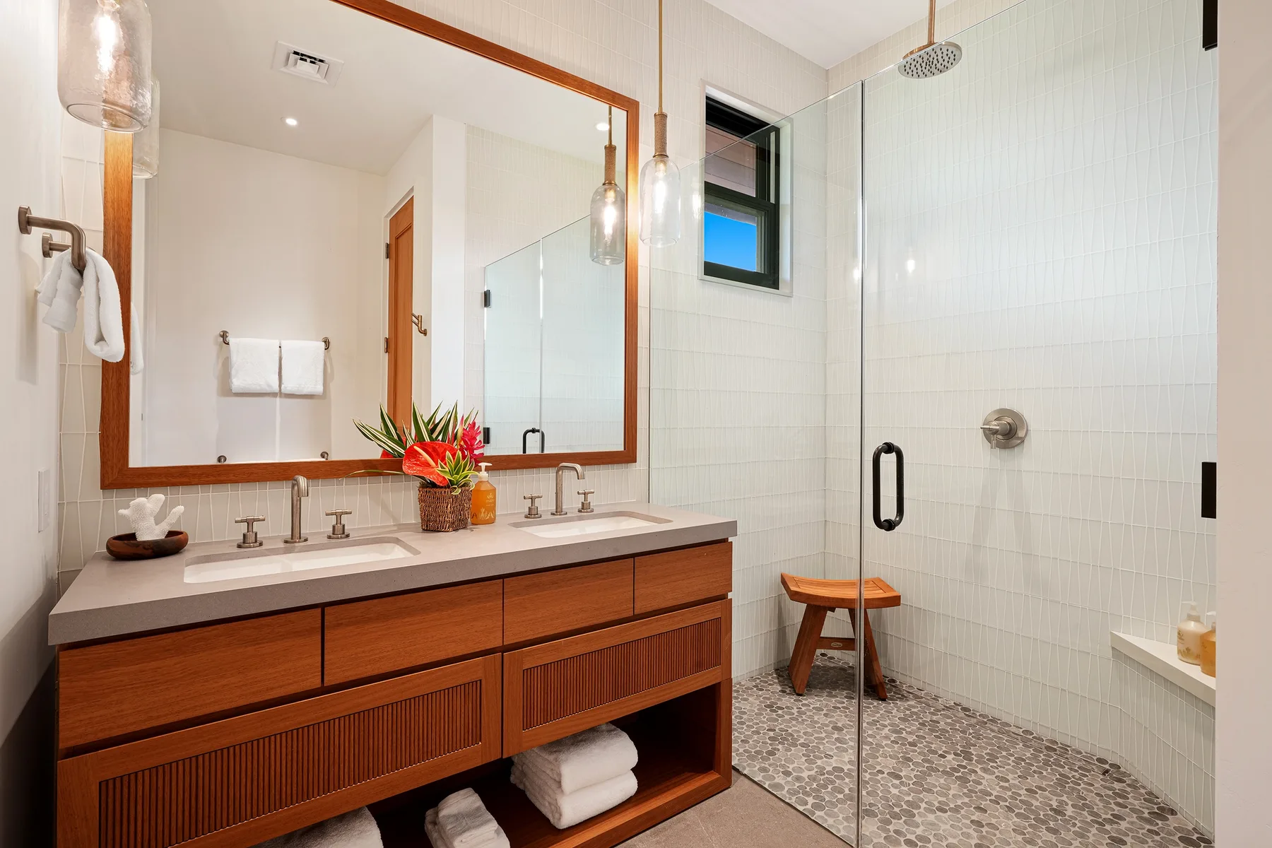 Un baño luminoso con un tocador largo y una ducha con mampara de vidrio.