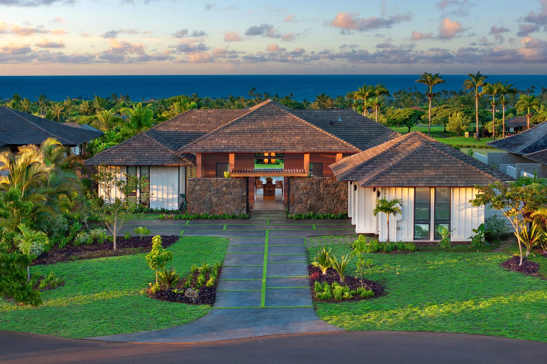Un edificio bajo de estilo resort da a un jardín, con el océano visible al fondo.