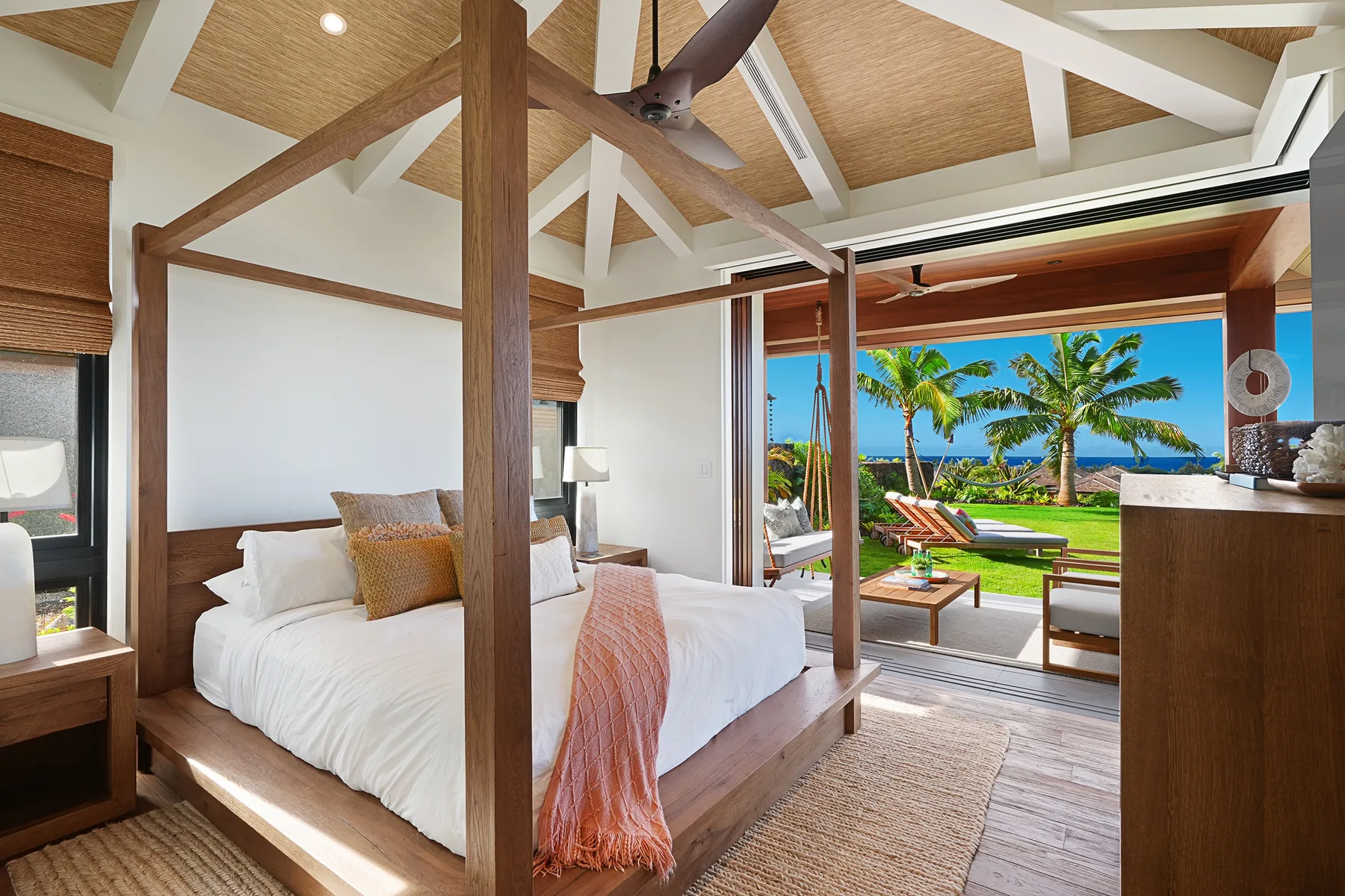 Un dormitorio con cama con dosel se abre a un patio y una vista con palmeras.