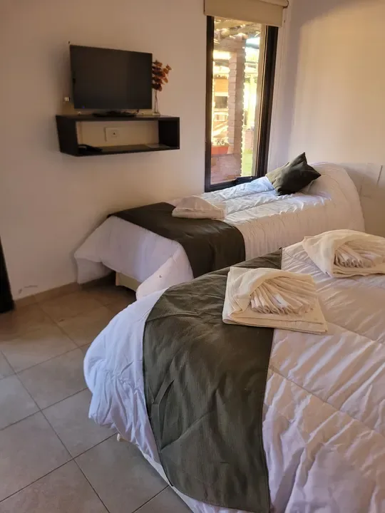Toallas dobladas sobre las camas, con un televisor y una ventana que da a la galería del patio.