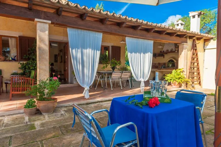 A patio dining area with a blue-covered table and seating beneath a pergola.
