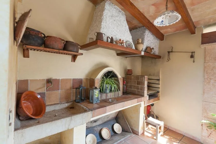 A rustic kitchen with a tiled counter and a small arched alcove.