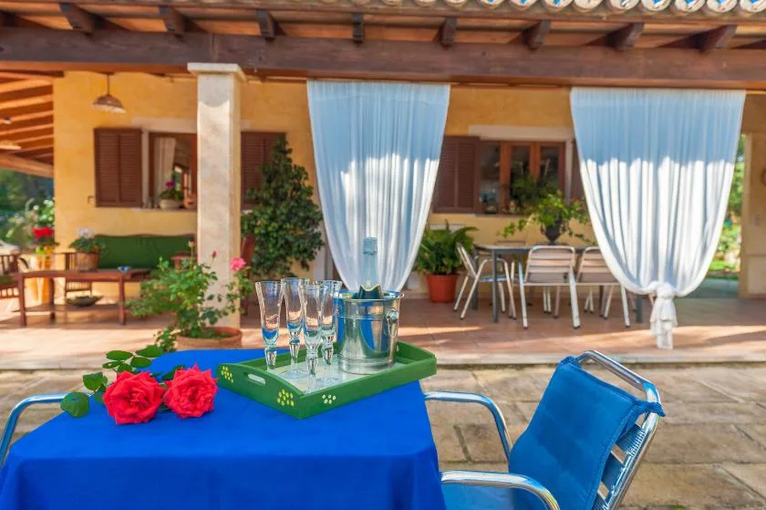 A covered outdoor dining patio with a blue table and seating.