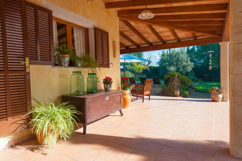 A covered patio with wooden beams opens onto a garden.