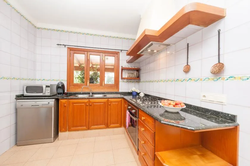 A tiled kitchen with wooden cabinets, a countertop, and a window.