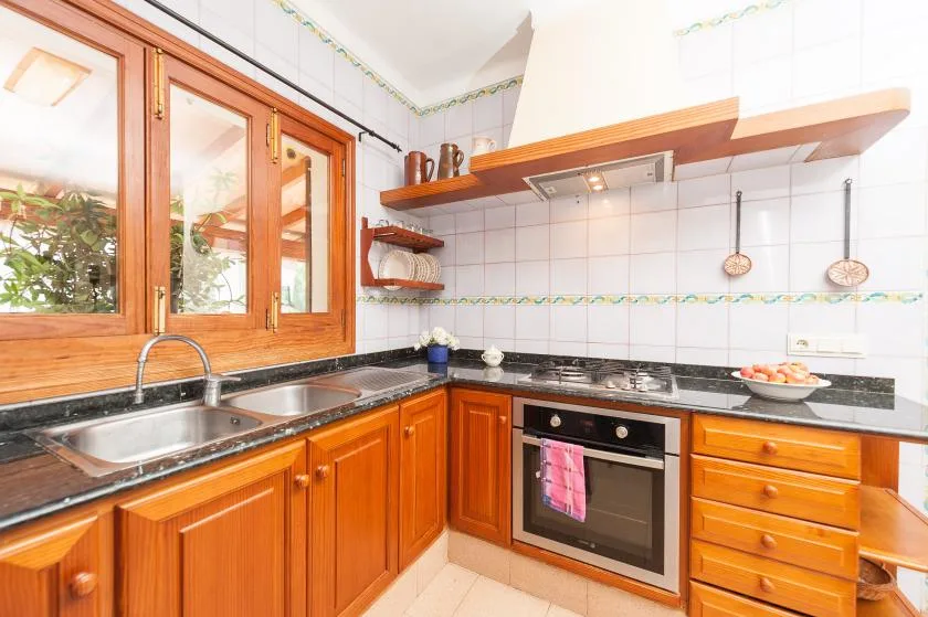 A tiled kitchen with wooden cabinets, a countertop, and a window.