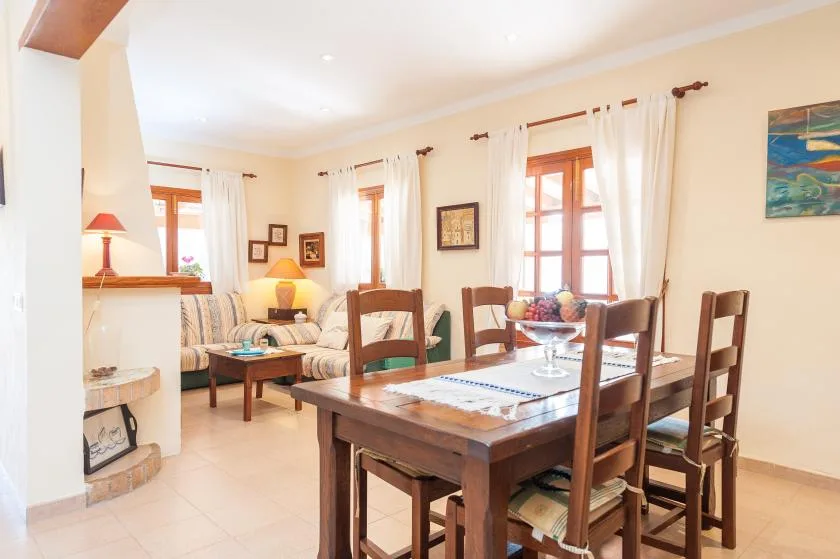 A dining area with a wooden table and seating beside a bright living room.