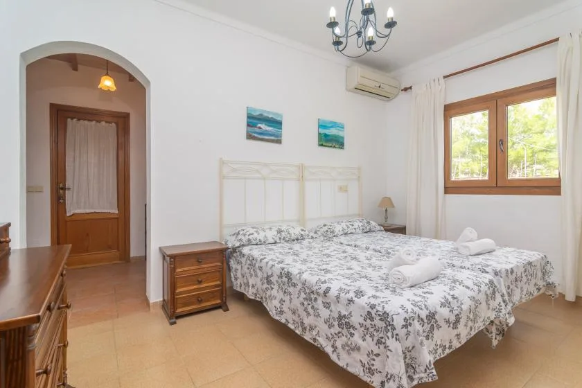 A bedroom with a double bed, bedside tables, and a window.