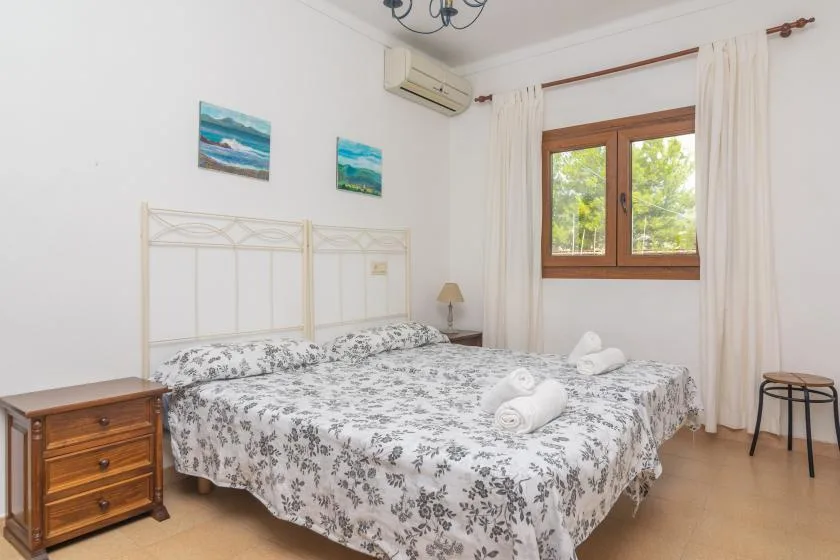 A bedroom with a large bed, patterned bedding, and a window with curtains.