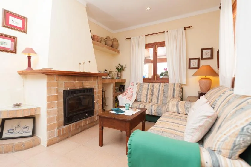 A living room with a brick fireplace, seating, and a wooden coffee table.