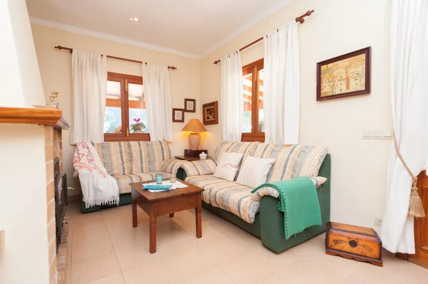 A bright living room with striped seating, a wooden coffee table, and curtained windows.