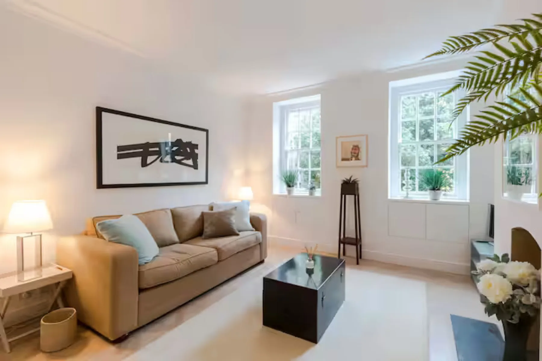 A bright living room with a sofa, coffee table, and tall windows.