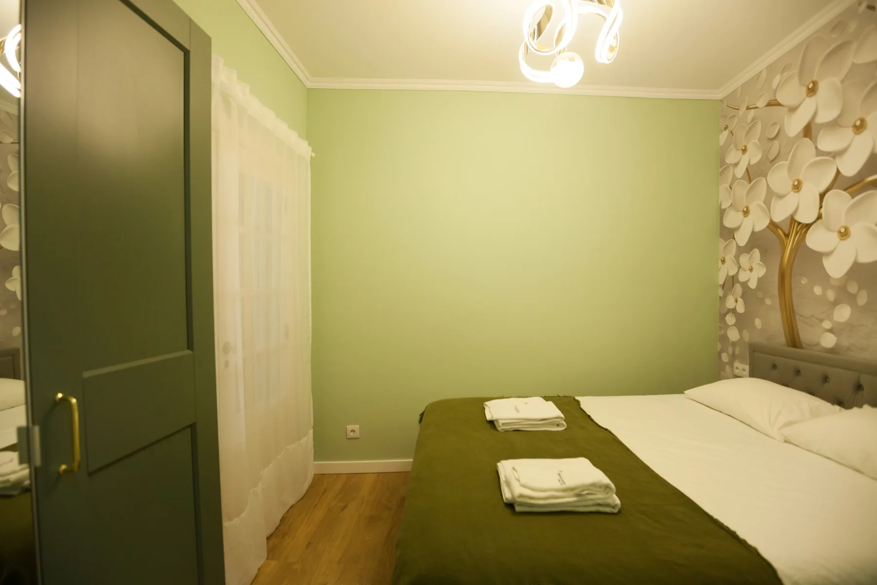 A bedroom with a neatly made bed and decorative wall panels.