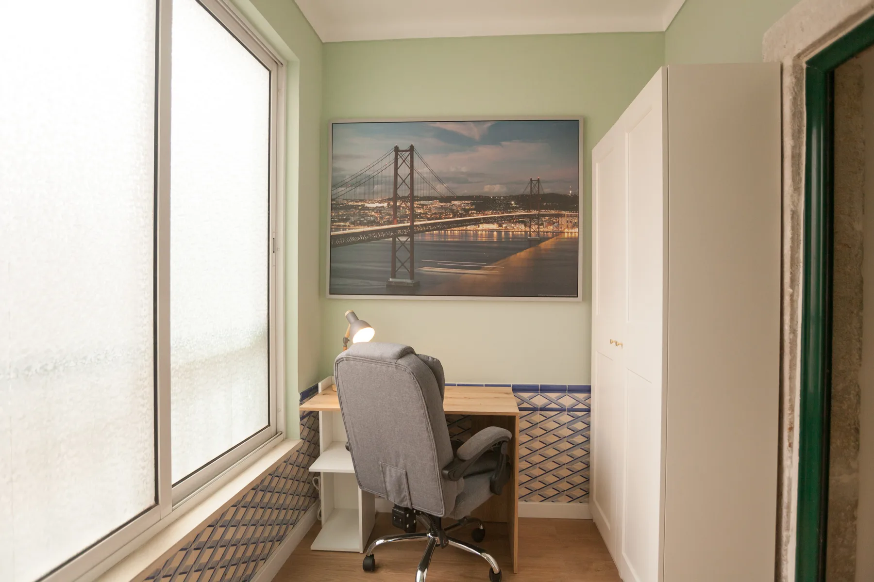 A small workspace with a desk and chair beside a large window.