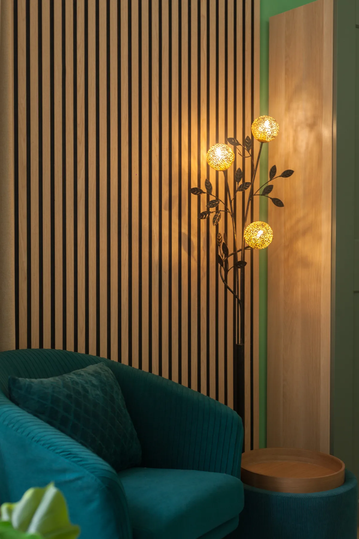A living room with teal seating beside a glowing floor lamp.