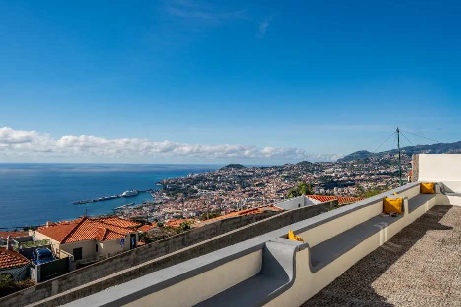 A rooftop terrace overlooks a coastal city and the sea.