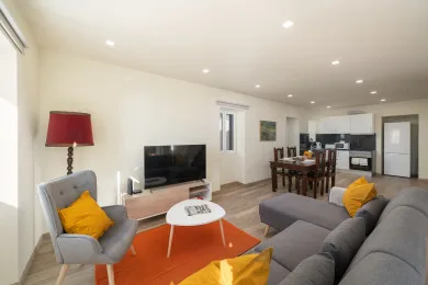 A living and dining area with gray seating, a television, and a dining table.