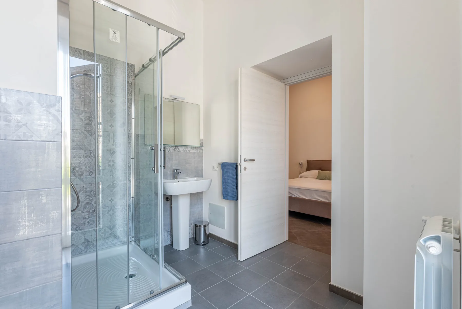 A bathroom with a glass shower, sink, and an open doorway.