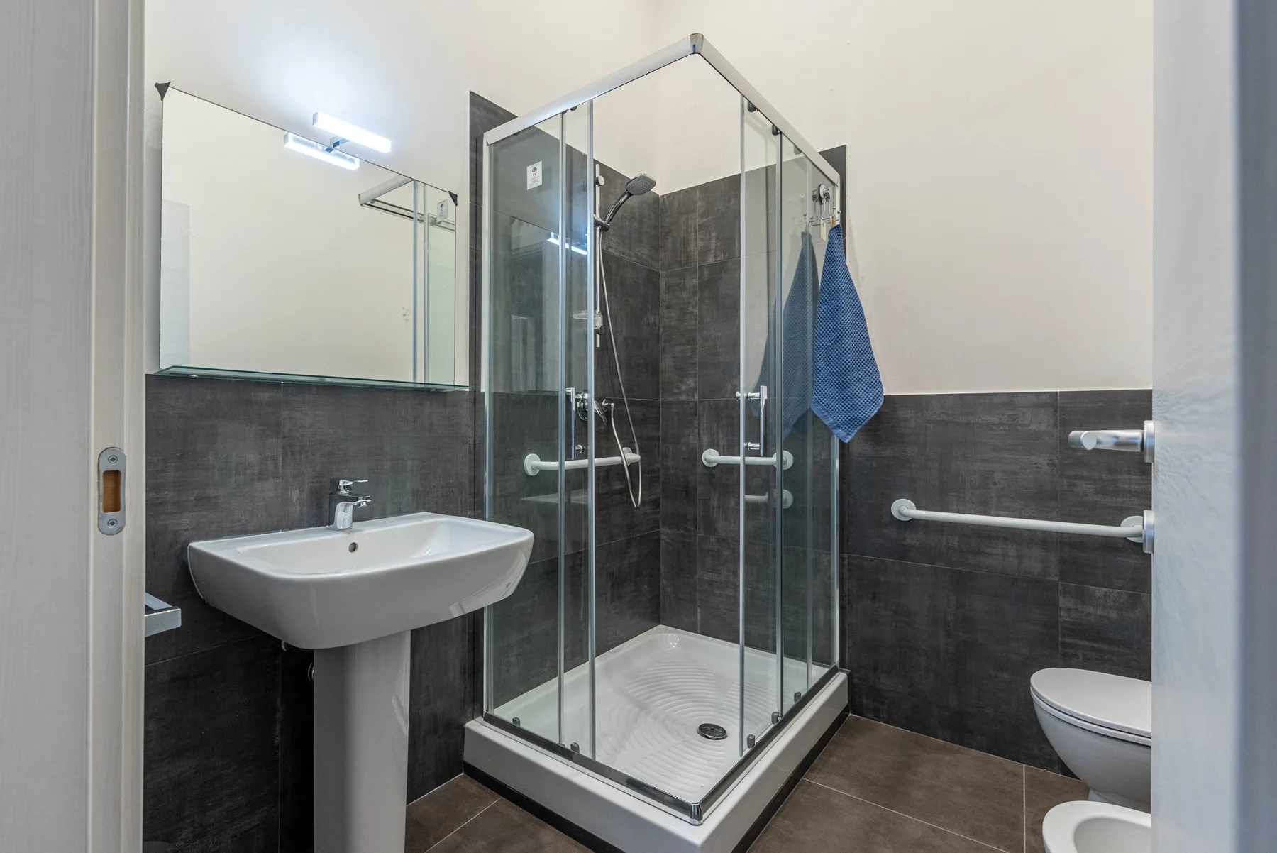 A bathroom with a glass shower, sink, and toilet.