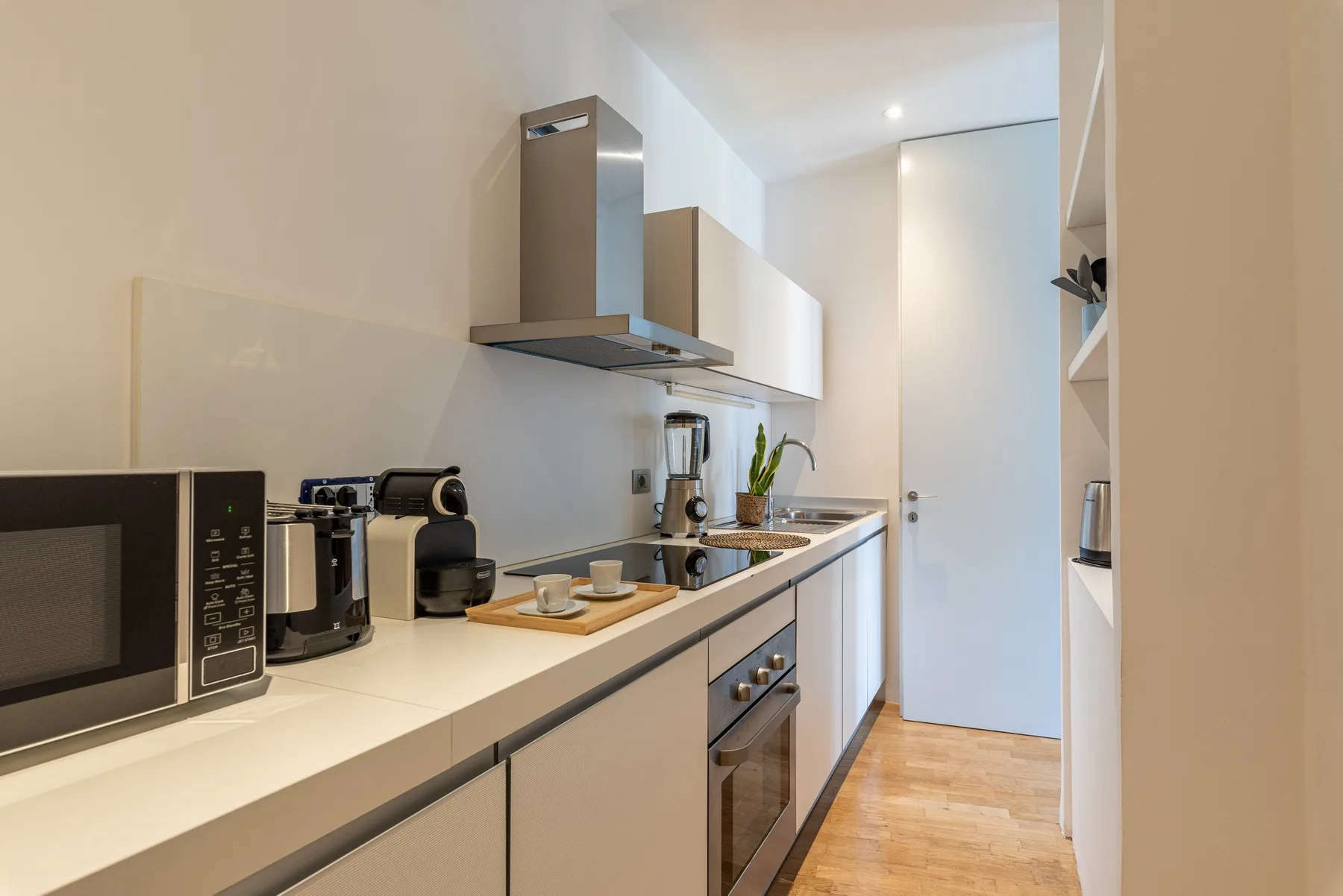 A narrow kitchen with a long counter, appliances, and cabinetry.
