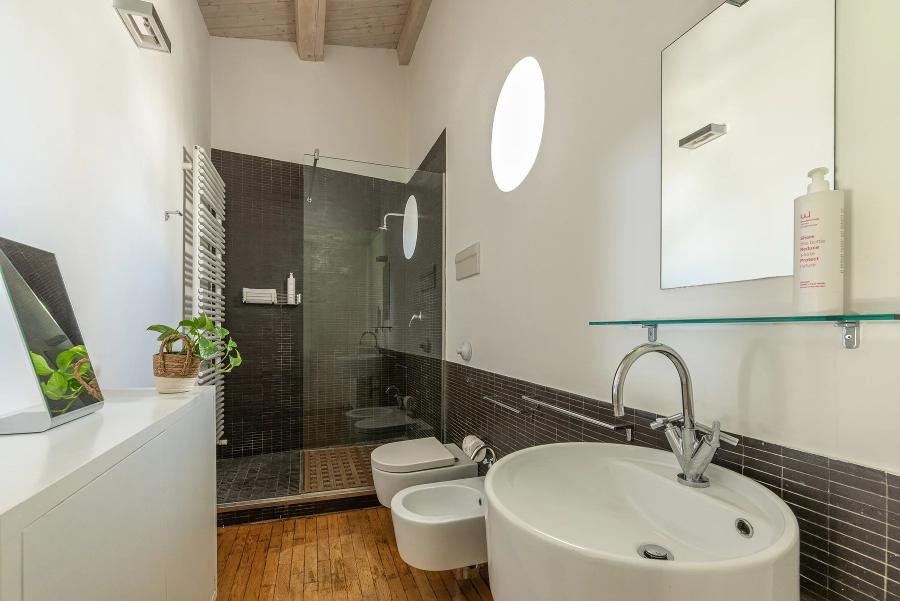 A bright bathroom with a sink, toilet, and glass shower area.