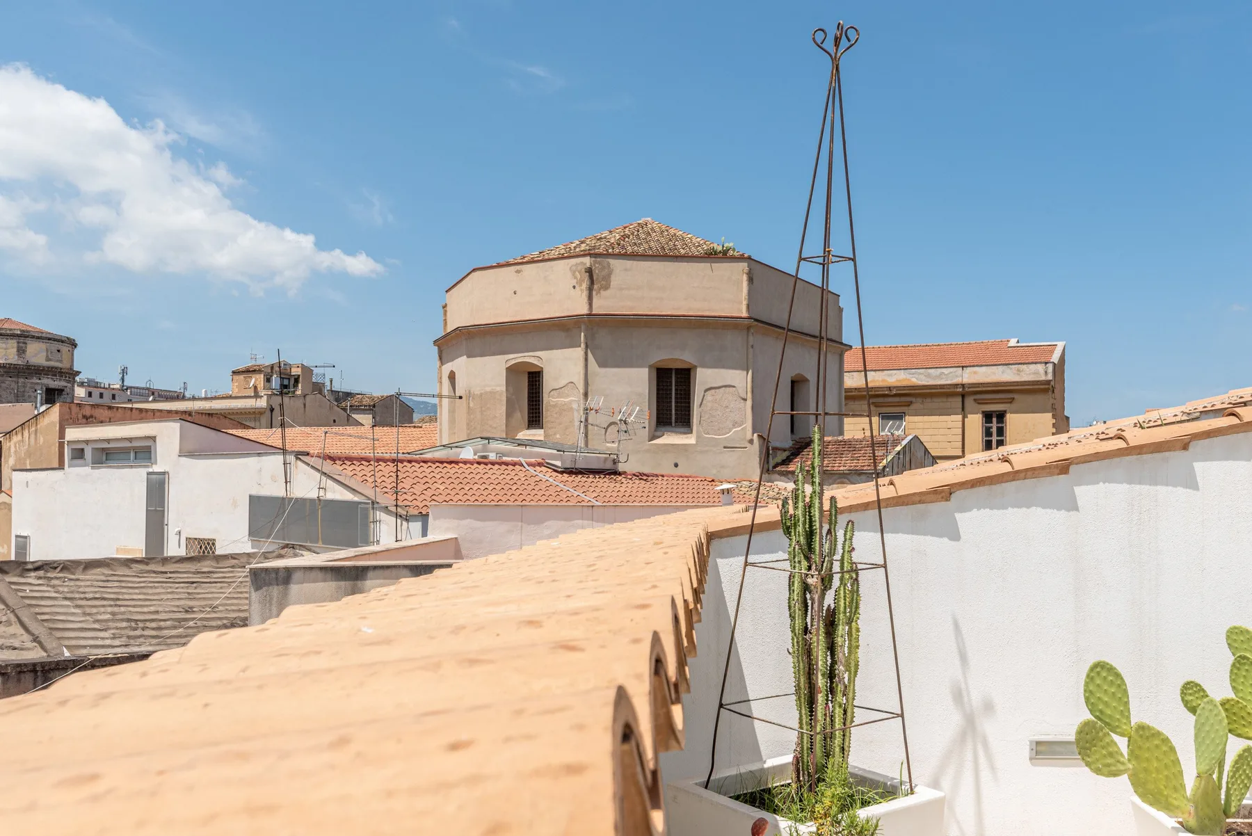 A rooftop terrace overlooks nearby buildings beneath a clear blue sky.