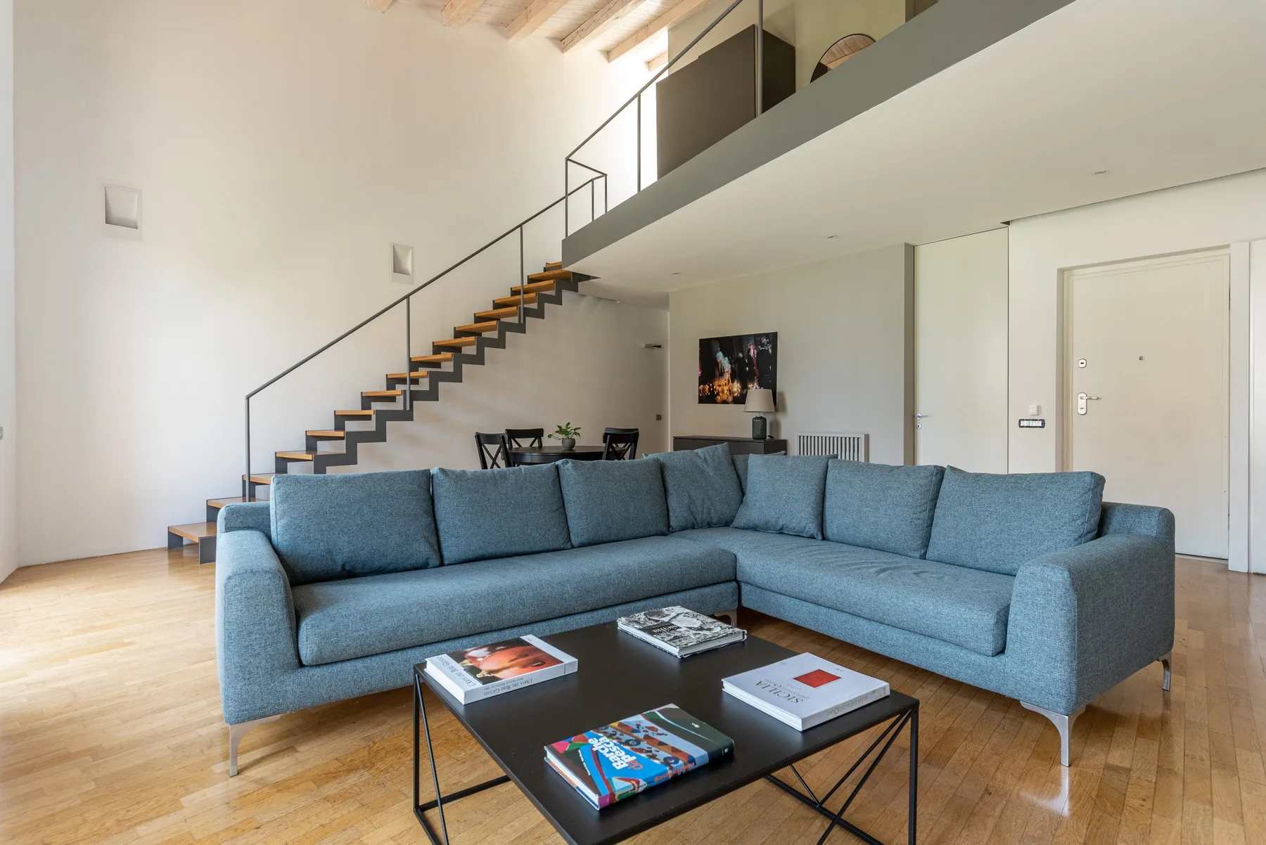 A bright living room with blue seating and a staircase leading to an upper level.