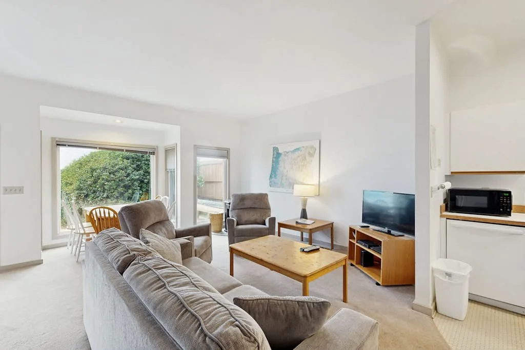 Una sala luminosa con asientos alrededor de una mesa de centro y un televisor.