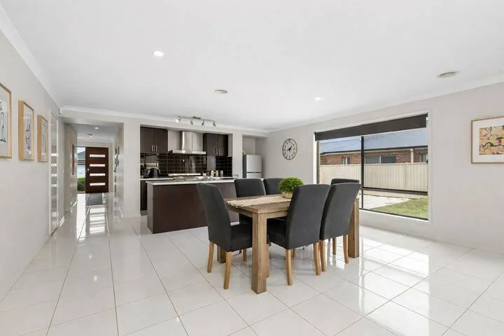 A dining area with a wooden table and dark upholstered seating beside the kitchen.