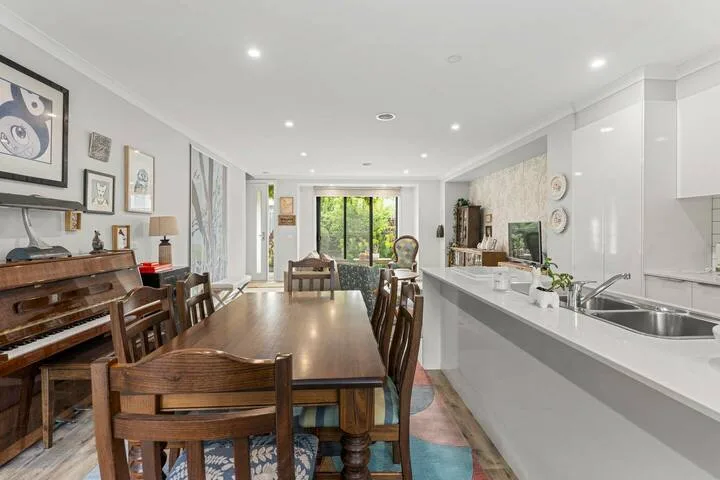 An open dining and kitchen area with a long wooden table and white counter.