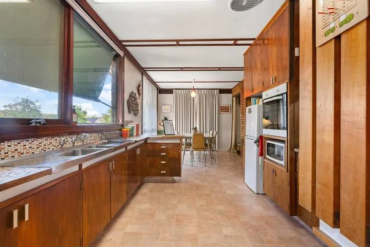 A long kitchen with wooden cabinets, a counter, and a dining table at the far end.