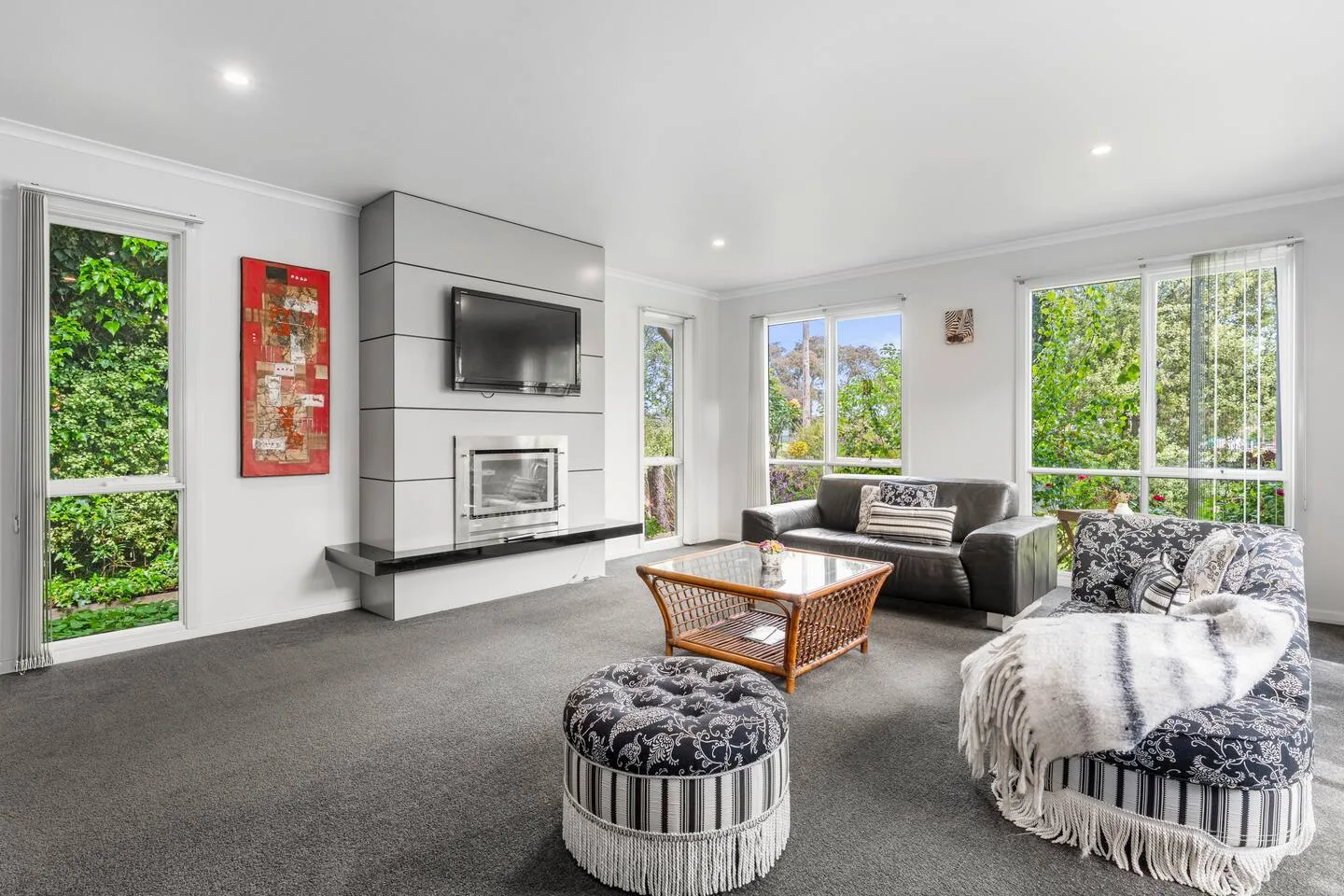 The main living area offers a bright setting where leafy views, generous seating, and the modern fireplace create an inviting place to slow down after a day out.