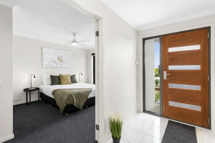 A bedroom is visible through an open doorway beside a wooden entry door.