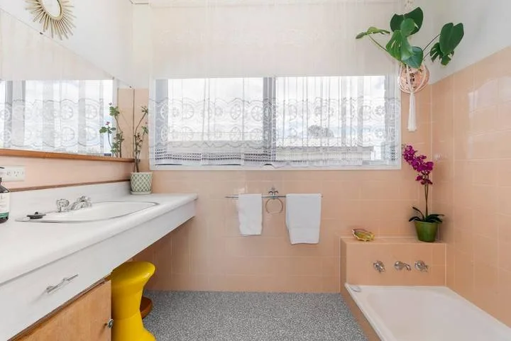 A bathroom with a wide sink counter and a bathtub beside the window.