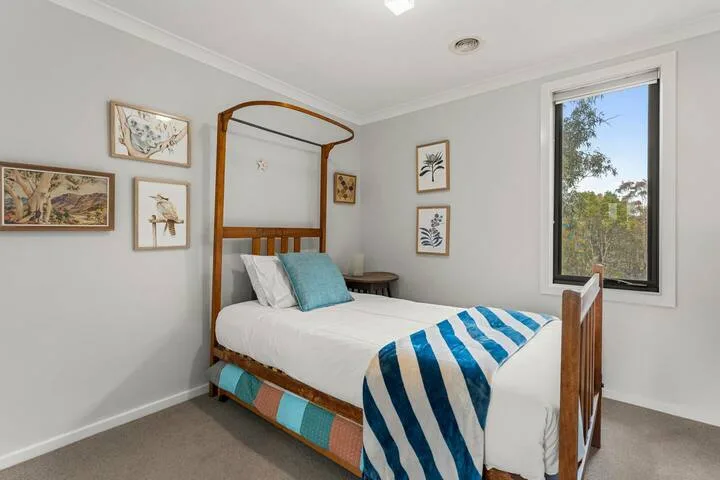 A bedroom with a wooden bed, striped blanket, and framed wall art.