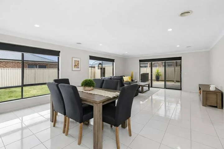 A bright open-plan living and dining area with large windows and tiled flooring.
