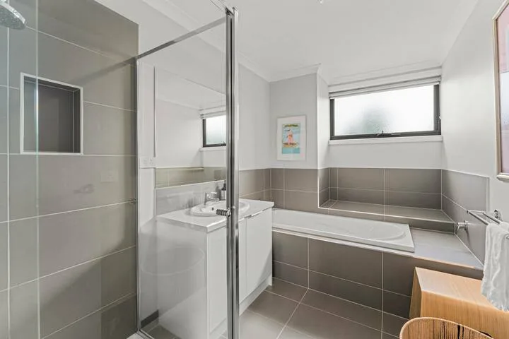 A tiled bathroom with a bathtub, shower, and vanity.