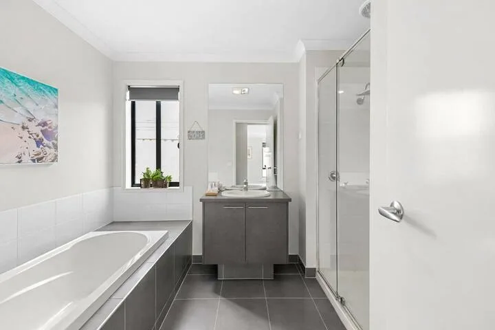 A bright bathroom with a bathtub, vanity, and glass shower.