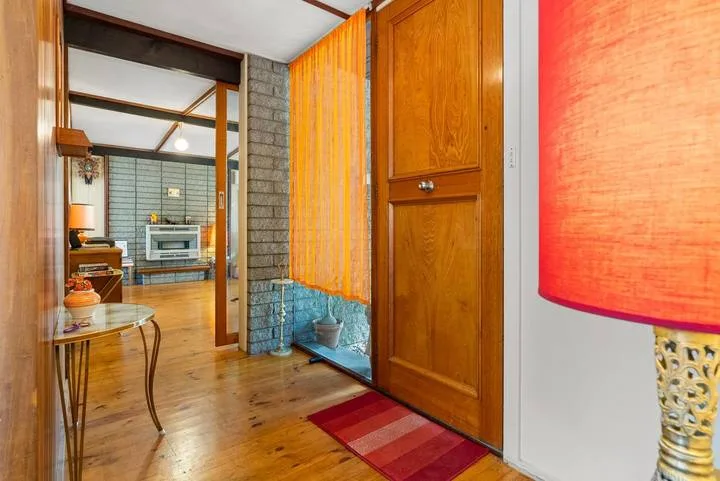 A wood-floored interior with a wooden door and a view into a tiled room.
