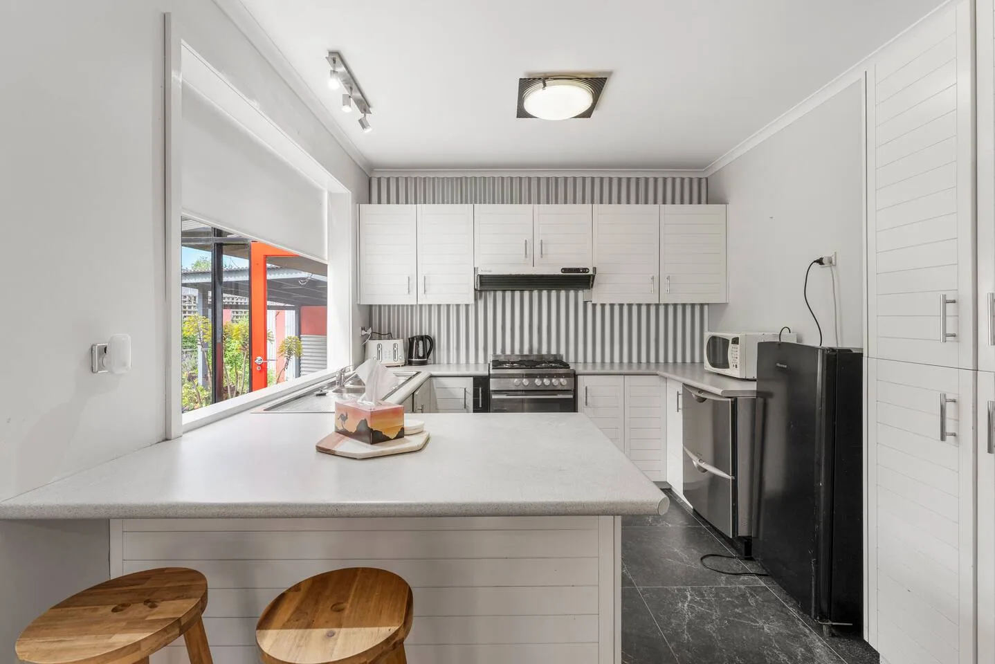 A bright kitchen with white cabinetry, a central island, and stainless steel appliances.