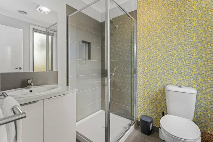 A bathroom with a sink, toilet, and glass-enclosed shower.